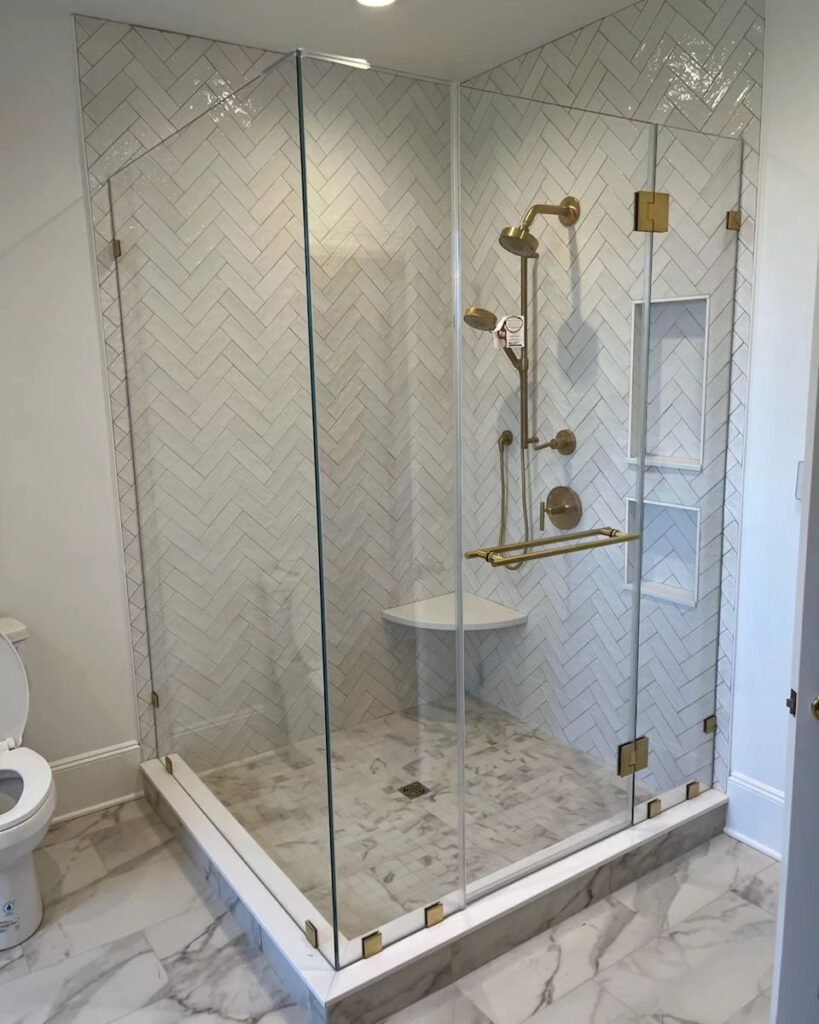 Walk-in shower with herringbone wall tile, niche and brass fixtures